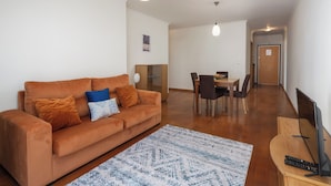 A living room with a sofa, a coffee table, and a TV stand. - Camélia's Apartment I –  Modern in Funchal (Funchal)