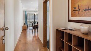 A hallway with wooden flooring, a wooden door, and a framed artwork on the wall. - Camélia's Apartment I –  Modern in Funchal (Funchal)