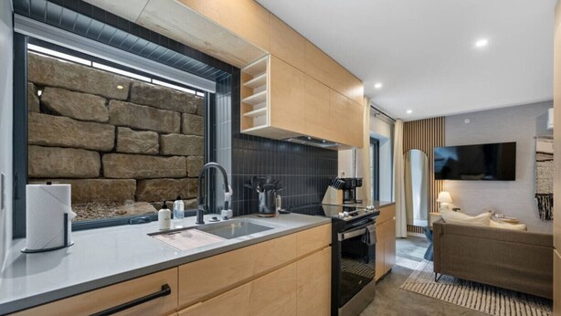 Una cocina moderna con una pared de acento de piedra, armarios de madera y un horno empotrado.
