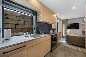 Una cocina moderna con una pared de acento de piedra, armarios de madera y un horno empotrado.