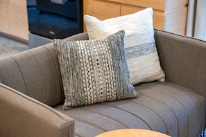 Un sofá gris con dos almohadones, uno con textura y el otro liso.