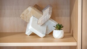 Una estantería de madera con un objeto que imita al mármol blanco y una pequeña planta en maceta.