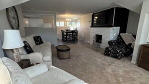 Ein geräumiges Wohnzimmer mit einem großen, weißen Sofa, einem Essbereich mit einer Kristallleuchtre und einem Kamin.
