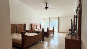 A spacious bedroom with a large bed, a smaller bed, a wooden dresser, and a ceiling fan. - Luxury home for 25, Lomas de Cocoyoc, swimming pool, jacuzzi, private garden (Fraccionamiento Lomas de Cocoyoc)