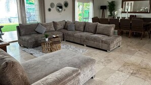 A spacious living room with a sectional sofa, a coffee table, and a dining area with a table and chairs. - Luxury home for 25, Lomas de Cocoyoc, swimming pool, jacuzzi, private garden (Fraccionamiento Lomas de Cocoyoc)