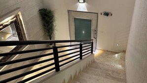 A staircase with a black railing, a round light fixture above, and a door with a green shutter. - Luxury home for 25, Lomas de Cocoyoc, swimming pool, jacuzzi, private garden (Fraccionamiento Lomas de Cocoyoc)