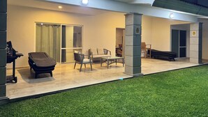A modern outdoor patio area with a dining table, chairs, a lounge chair, and a small table with a chair. - Luxury home for 25, Lomas de Cocoyoc, swimming pool, jacuzzi, private garden (Fraccionamiento Lomas de Cocoyoc)