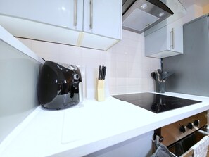 A kitchen with white cabinets, a black induction cooktop, and a wooden knife block.