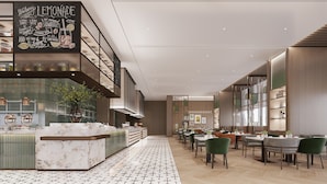 Um restaurante moderno com teto alto, balcão de mármore e diversas áreas de refeição com cadeiras verdes.