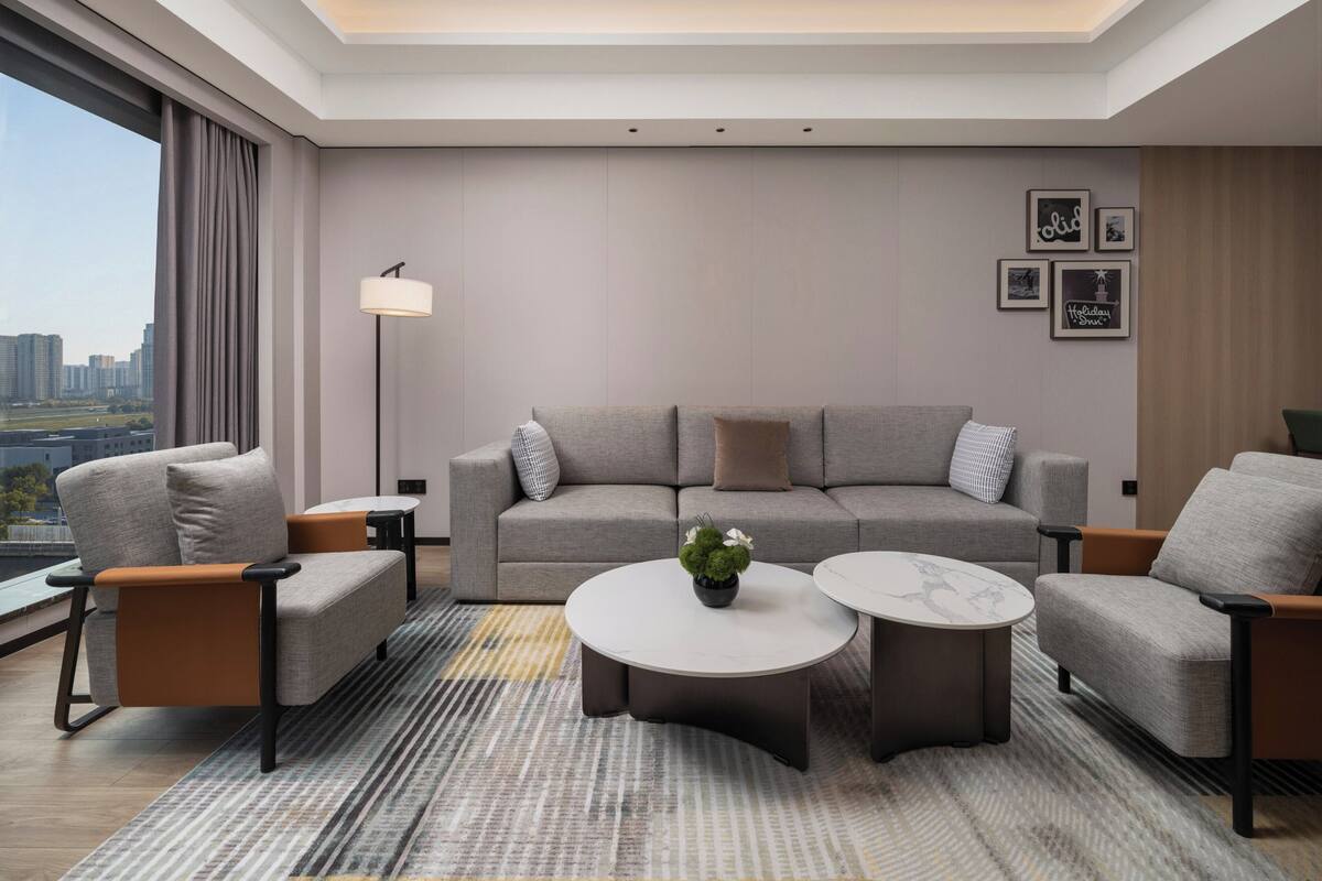 Una sala de estar moderna con un sofá, sillones, una mesa de centro y una lámpara de pie.