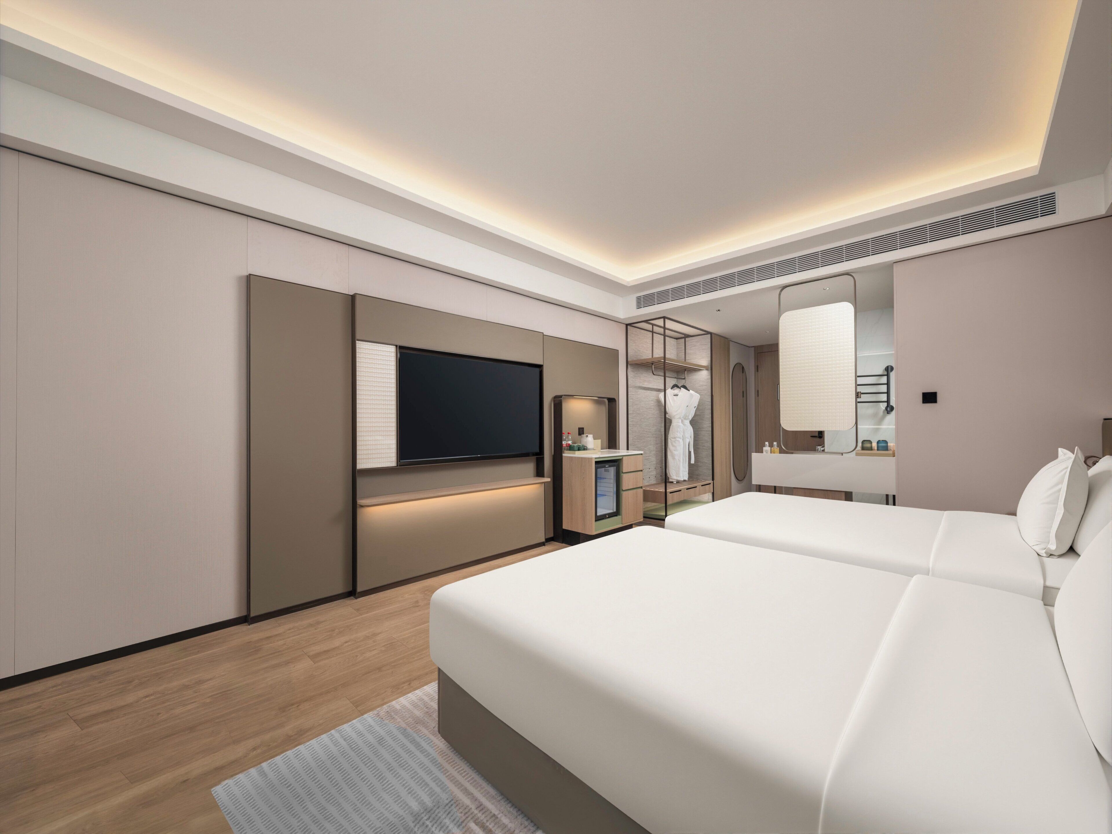 Une chambre d’hôtel moderne équipée d’un grand lit, d’une télévision, d’un miroir et d’une petite salle de bain.