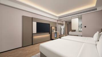 A modern hotel room with a large bed, a TV, a mirror, and a small bathroom area.