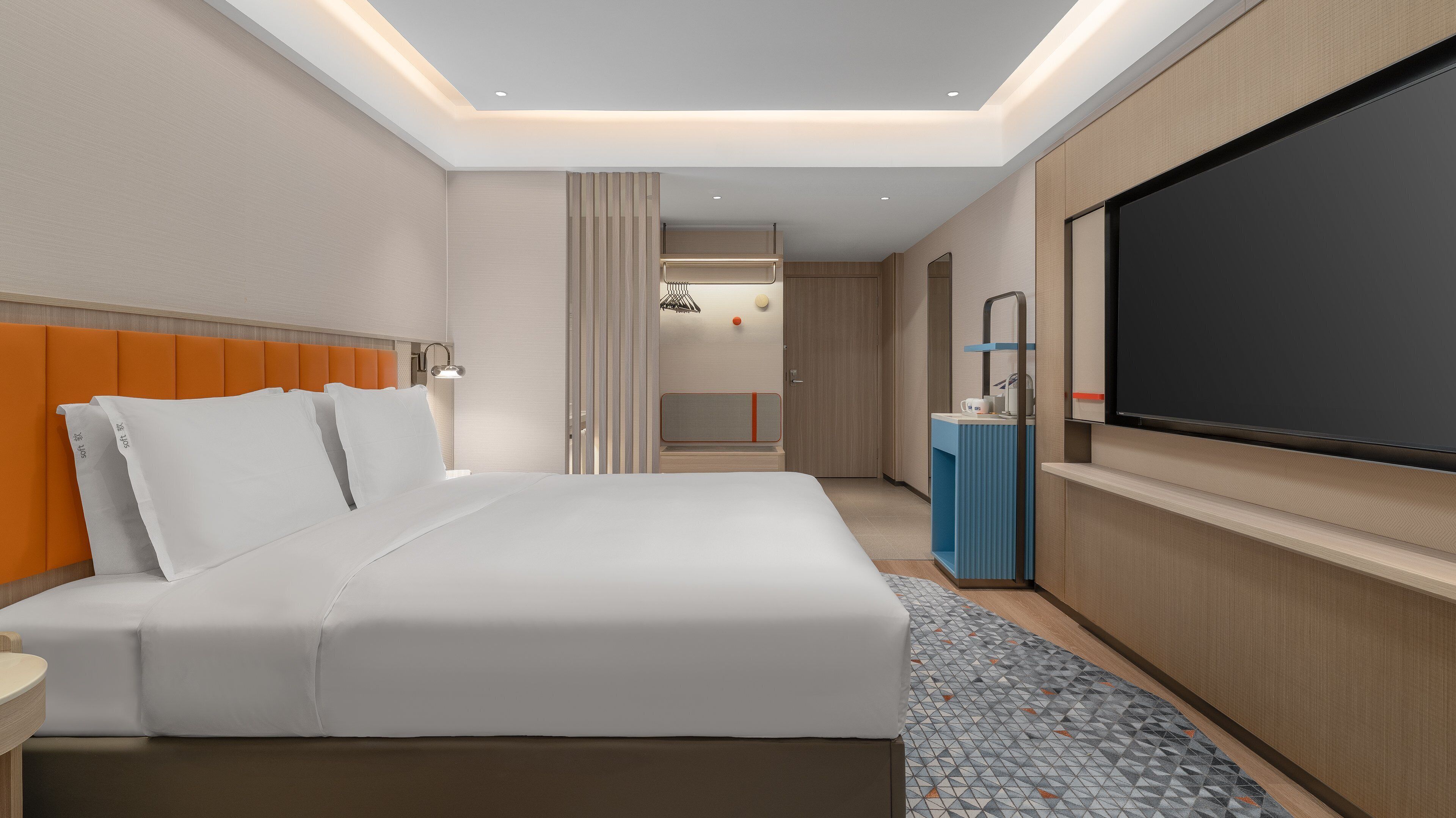 Habitación de hotel con cama, televisor, escritorio y baño a la vista.