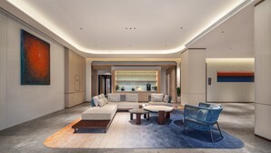 Un hall d’hôtel moderne avec un canapé d’angle, une table basse et un fauteuil bleu.