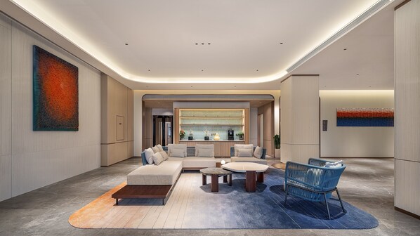 Un moderno vestíbulo de hotel con un sofá modular, una mesa de centro y una silla azul.