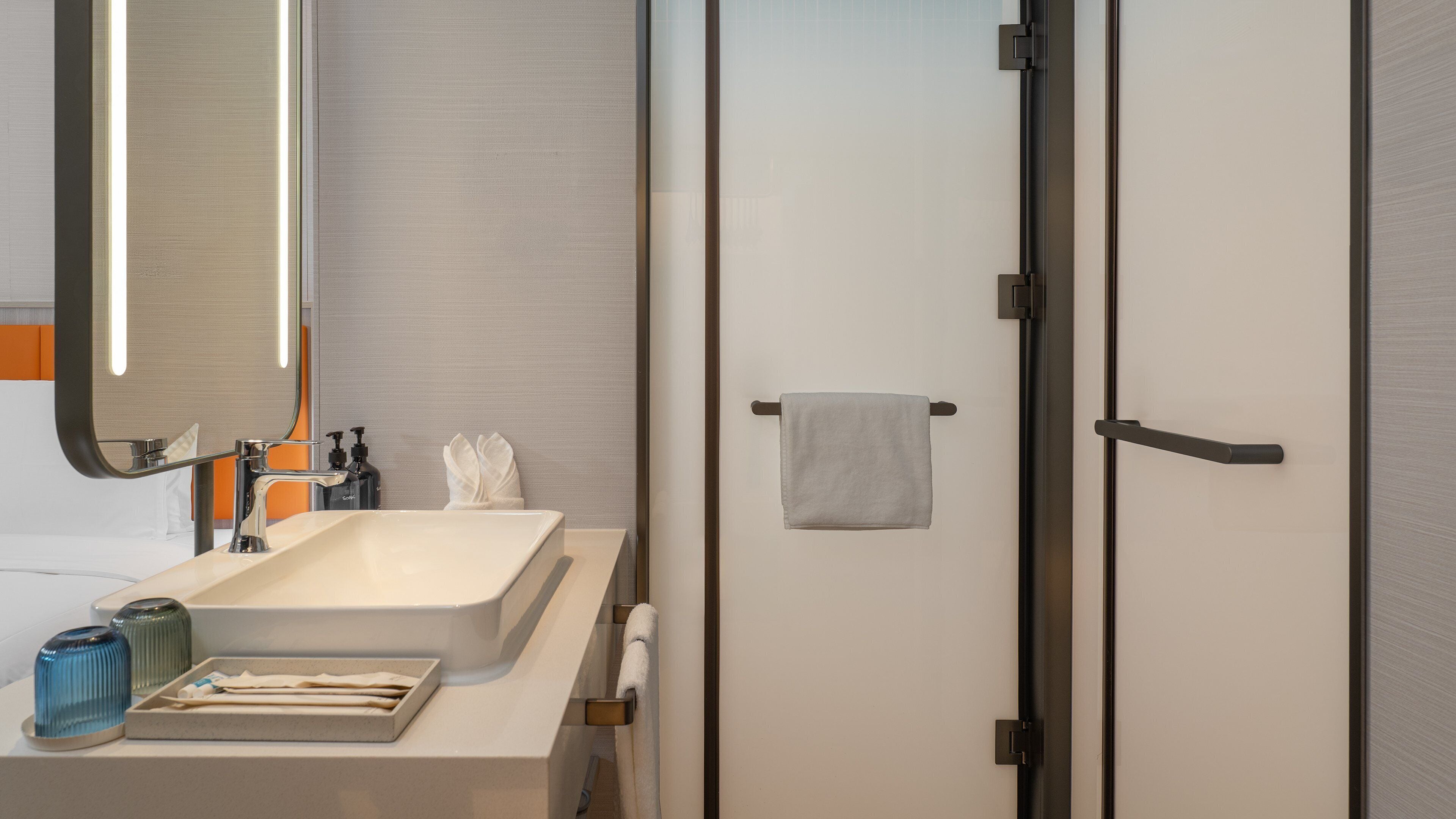 Un baño moderno con un lavamanos grande, un espejo y un perchero para toallas.