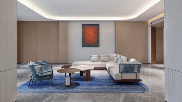 A modern living room with a sectional sofa, two armchairs, a coffee table, and a large abstract painting on the wall.