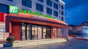 A hotel with a modern facade, large glass windows, and a prominent green logo. - Holiday Inn Express Shenzhen Dapeng Nan'ao by IHG (Shenzhen)