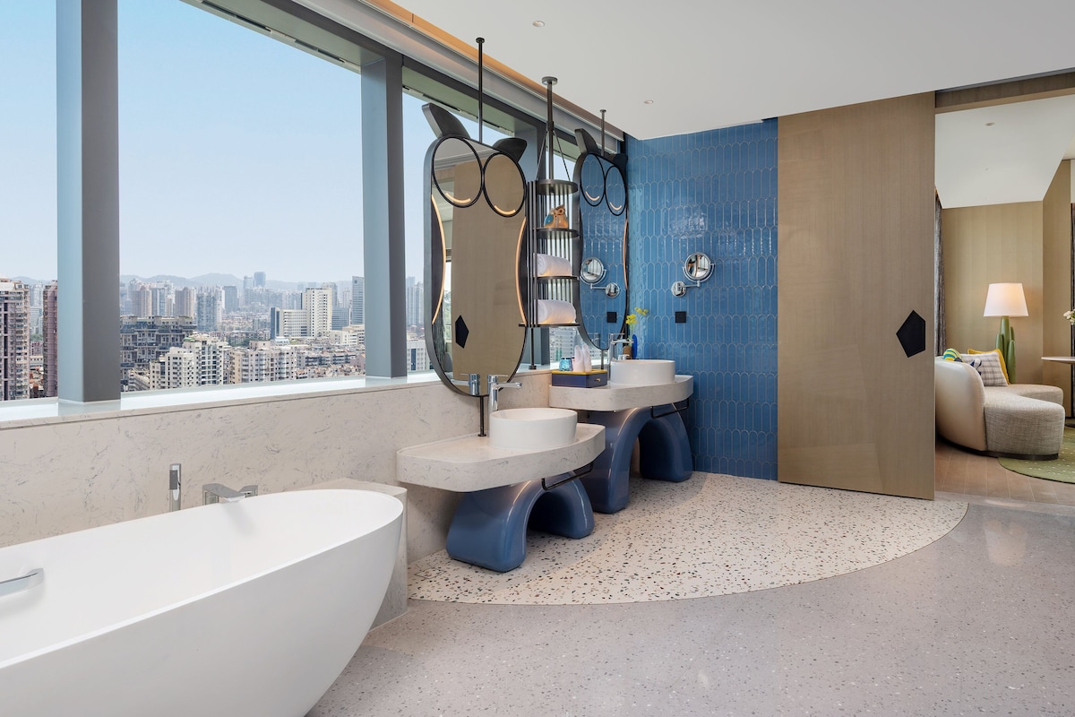 A modern bathroom with a bathtub, two sinks, and a large mirror.
