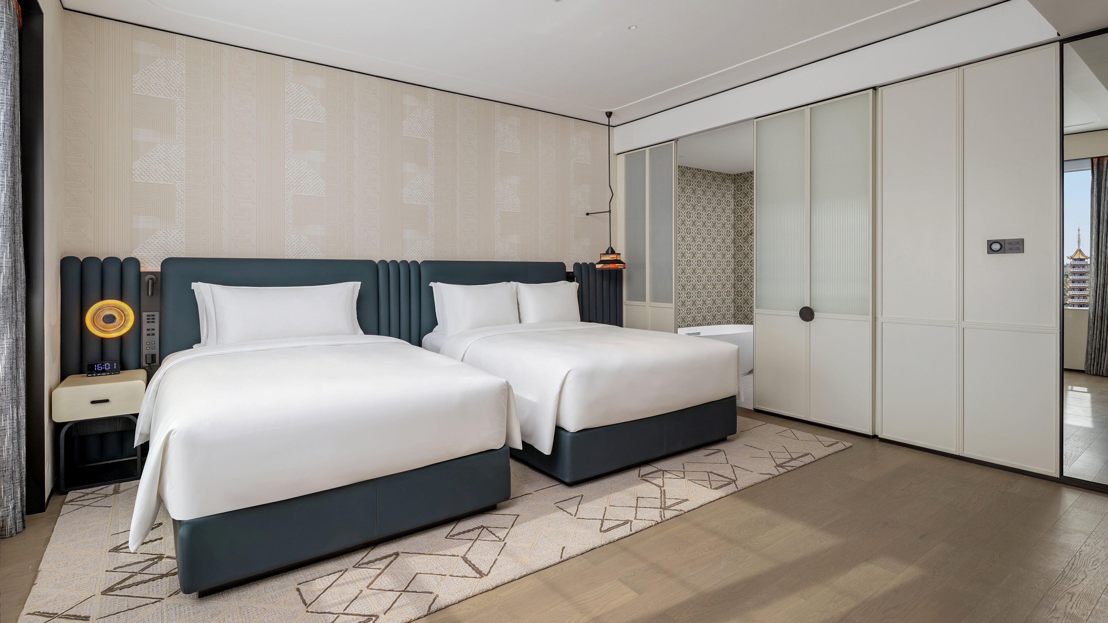 Una habitación de hotel moderna con cama, mesitas de noche, un espejo y un armario.