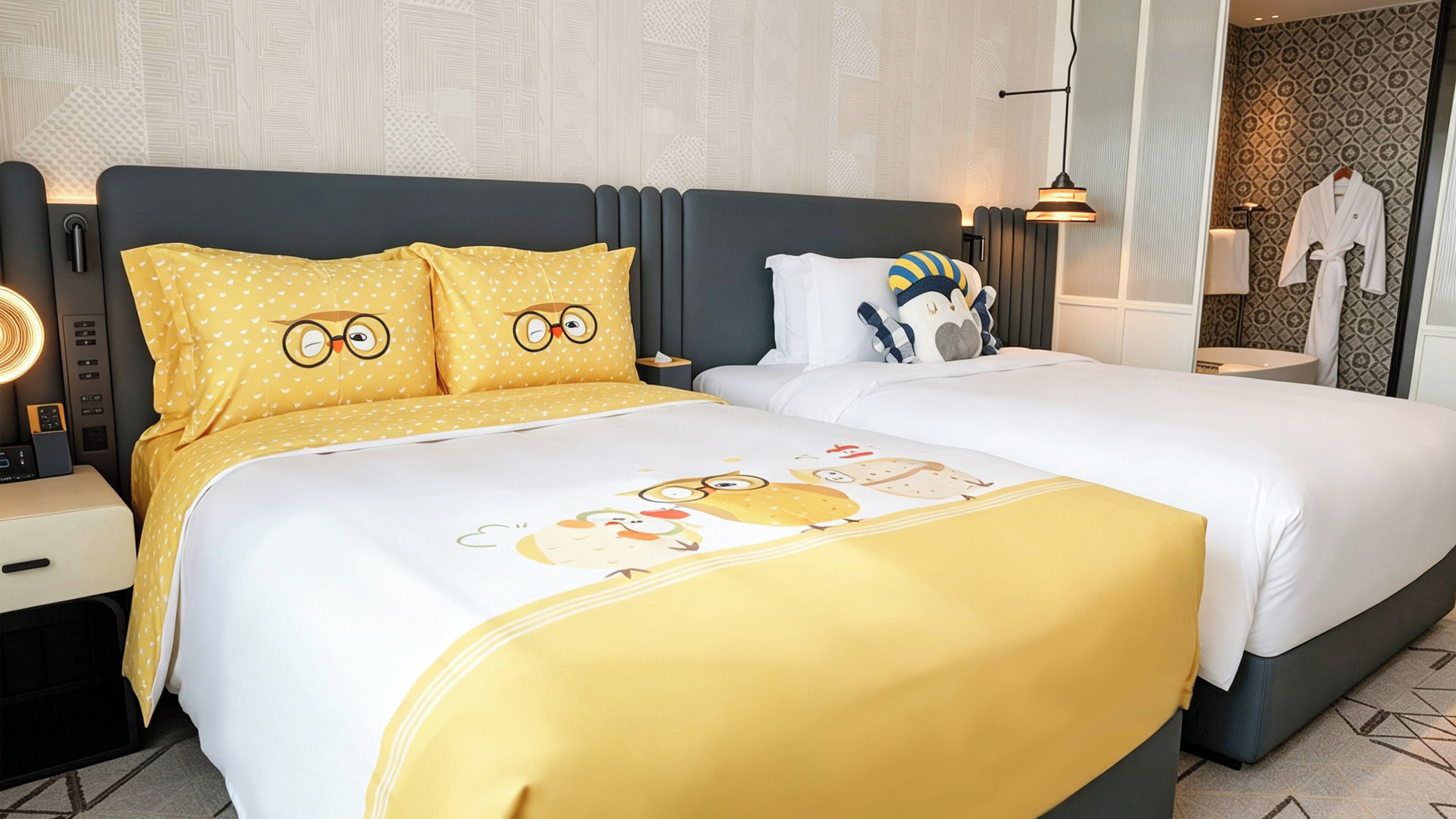 Habitación de hotel con una cama grande, dos mesitas de noche, una lámpara y una bata colgada en la pared.