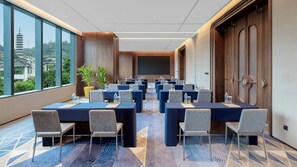 A conference room with multiple tables and chairs, large windows with a view of a pagoda, and a carpeted floor. - Xiamen Sm City By Ihg (Xiamen)