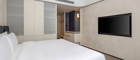 A modern hotel room with a large bed, a flat-screen TV mounted on the wall, and a walk-in closet.