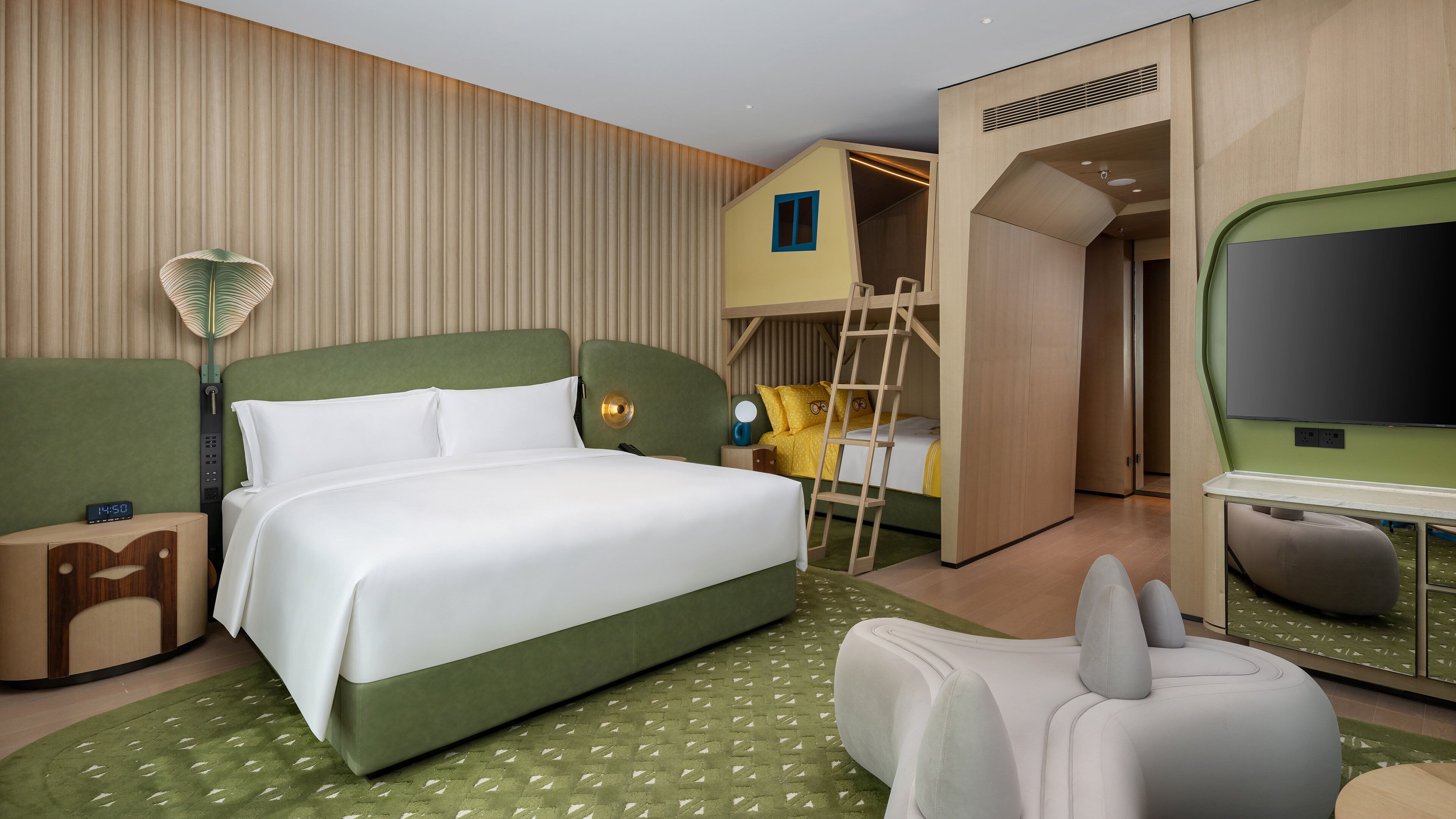 Quarto de hotel com cama, escrivaninha, televisão e guarda-roupa.