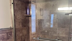 A modern bathroom with a glass-enclosed shower, a white toilet, and a marble-tiled shower area. - Spacious 3BR/2Bath Home - Retreat w/ Modern Amenities (Harper Woods)