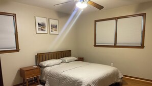 A bedroom with a bed, nightstands, a wooden headboard, a ceiling fan, and two windows with blinds. - Spacious 3BR/2Bath Home - Retreat w/ Modern Amenities (Harper Woods)