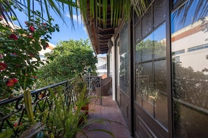 A narrow outdoor corridor with a metal railing, potted plants, and a view of a building through large windows. - Almeirim House (Almeirim)