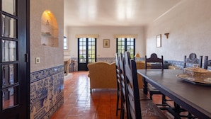 A dining area with a long table, chairs, and a patterned tile floor.
