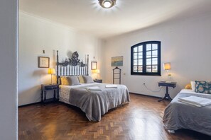 A bedroom with two beds, wooden flooring, a large window, and a decorative headboard. - Almeirim House (Almeirim)