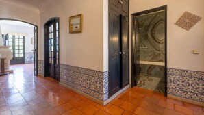 A hallway with a tiled floor, a black door, and a glass door with a marble pattern.