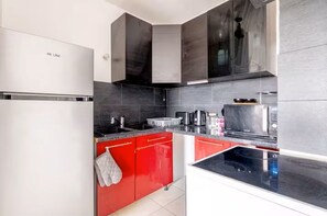 A modern kitchen with red cabinets, a black countertop, and a stainless steel refrigerator. - Head in the clouds Drancy (Near Paris, CDG) (Drancy)