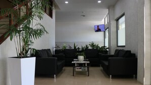 A modern lobby with black sofas, a coffee table, potted plants, and a TV screen. - Hotel Imperio Do Minho (Ponte de Lima)