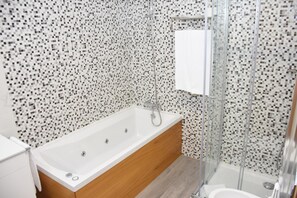 Un baño moderno con una bañera independiente, un box de ducha de vidrio y un lavabo blanco.