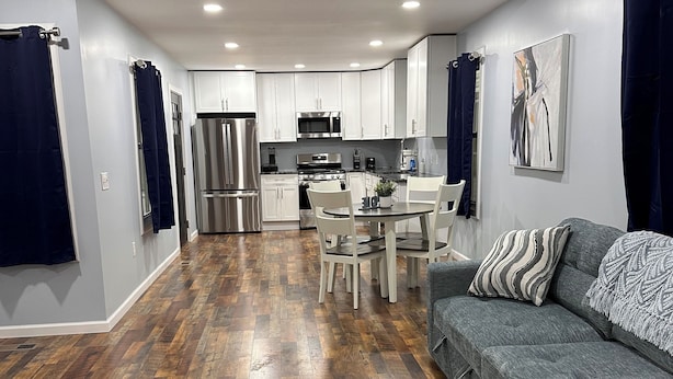 A modern kitchen with white cabinets, stainless steel appliances, and a dining area with a table and chairs. - Gray Getaway (Gettysburg)