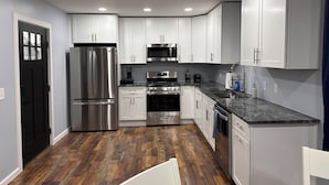 A modern kitchen with white cabinets, stainless steel appliances, and a wooden floor. - Gray Getaway (Gettysburg)