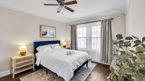 A bedroom with a bed, nightstands, a ceiling fan, a window with curtains, and a plant. - Beautifully Remodeled 2B/2BA Hyde Park (Chicago)