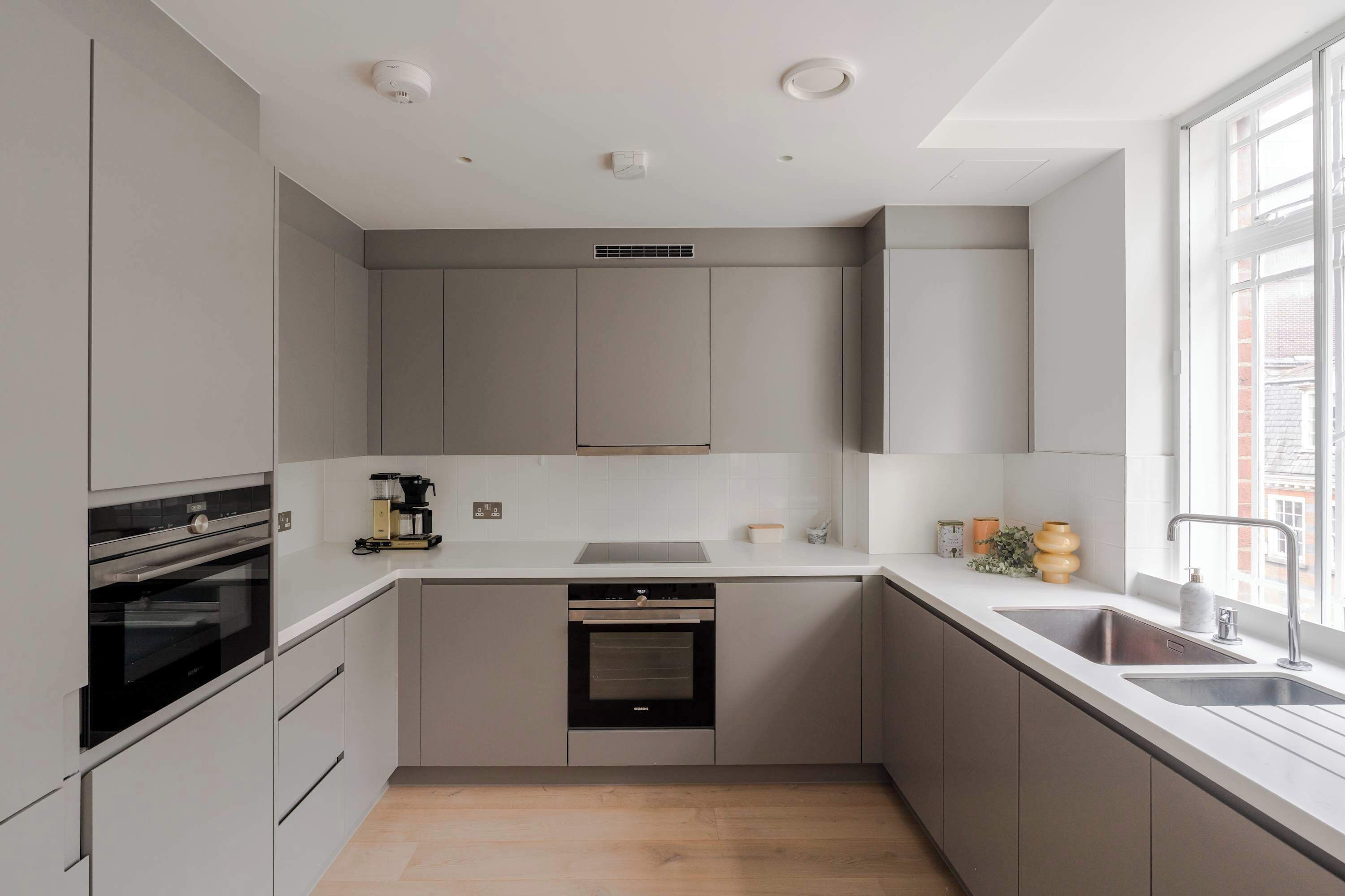 A modern kitchen with built-in appliances, a large window, and a minimalist design.