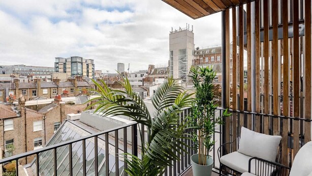 Un balcon offrant une vue sur le paysage urbain, avec des bâtiments et une haute structure.