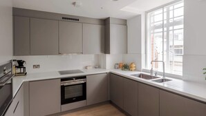 Une cuisine moderne dotée d’appareils électroménagers intégrés, d’une grande fenêtre et offrant une vue sur la ville.