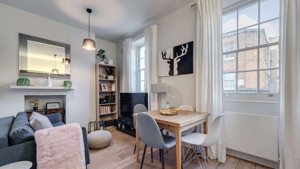 A modern living room with a sofa, a dining table with chairs, a TV, and a fireplace. - The Fox & Found - Fitzrovia - by Frankie (London)