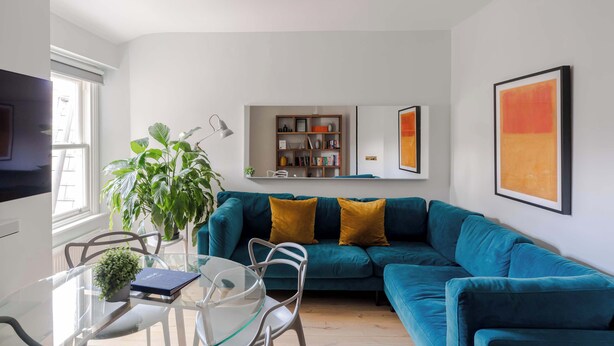 A modern living room with a teal sofa, glass coffee table, and a bookshelf. - Stairway To Heaven - Fitzrovia - by Frankie Says (London)