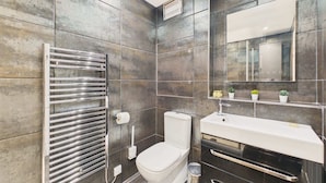 Une salle de bain moderne avec des toilettes intégrées, un meuble-lavabo avec un miroir et un porte-serviettes.