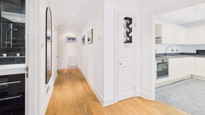 Une cuisine moderne avec des meubles blancs, un four encastré et un dosseret de carrelage gris.