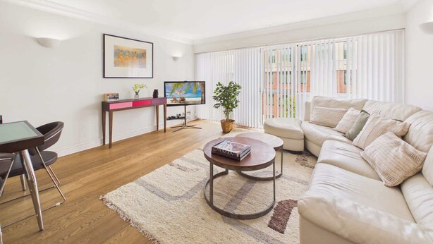 Un salon moderne avec un canapé, une table basse et un téléviseur. Il y a également un coin repas avec une table et des chaises.