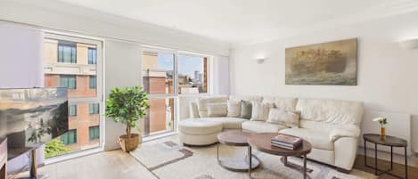 A modern living room with a sofa, coffee table, and a painting on the wall.