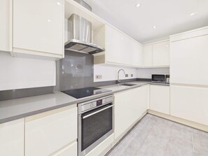 A modern kitchen with white cabinetry, a stainless steel range hood, a built-in oven, and a microwave. - Charter Luxe - Covent Garden - By Frankie Says (London)